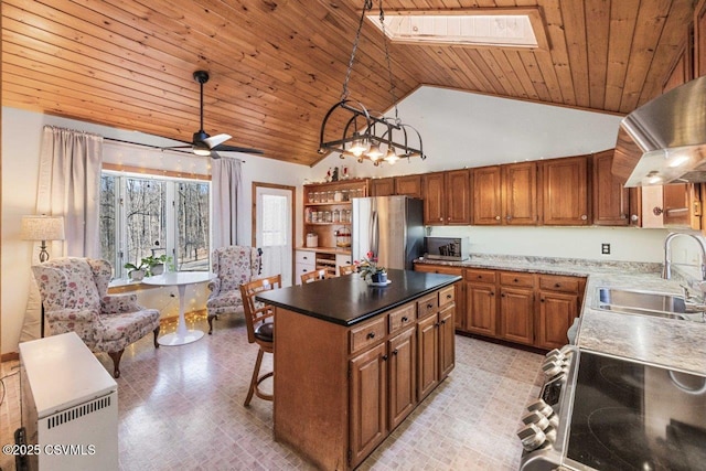 kitchen featuring stainless steel appliances, hanging light fixtures, brown cabinetry, a kitchen island, and a sink