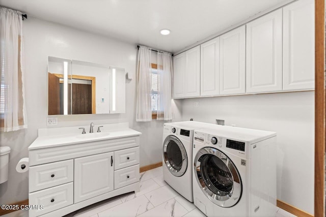 clothes washing area with laundry area, a sink, baseboards, marble finish floor, and washing machine and clothes dryer