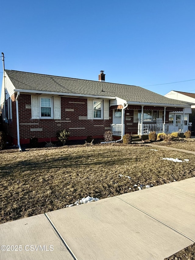 single story home featuring a porch, brick siding, a chimney, and roof with shingles