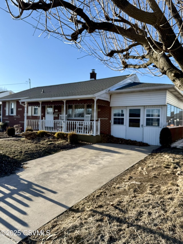 single story home with roof with shingles, a chimney, and brick siding