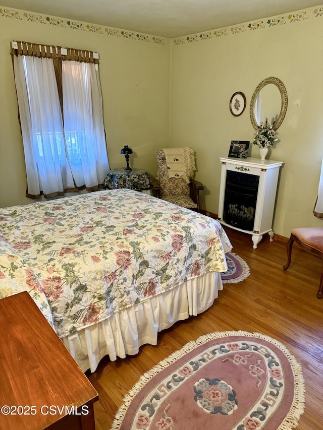 bedroom with a fireplace, baseboards, and wood finished floors