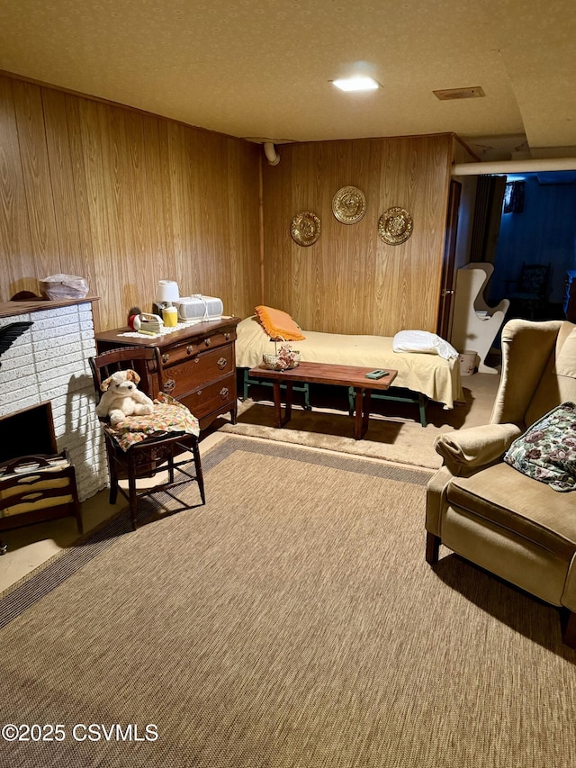 sitting room featuring carpet floors, a brick fireplace, visible vents, and wooden walls