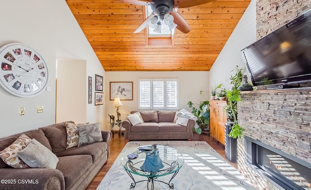 living room with wood ceiling, ceiling fan, wood finished floors, a stone fireplace, and high vaulted ceiling