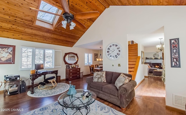 living room with visible vents, wooden ceiling, hardwood / wood-style floors, a lit fireplace, and ceiling fan with notable chandelier