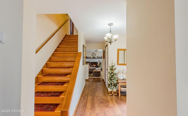 staircase featuring a notable chandelier and wood finished floors