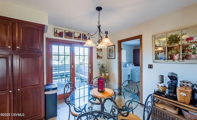 dining room with a chandelier, light tile patterned flooring, and separate washer and dryer