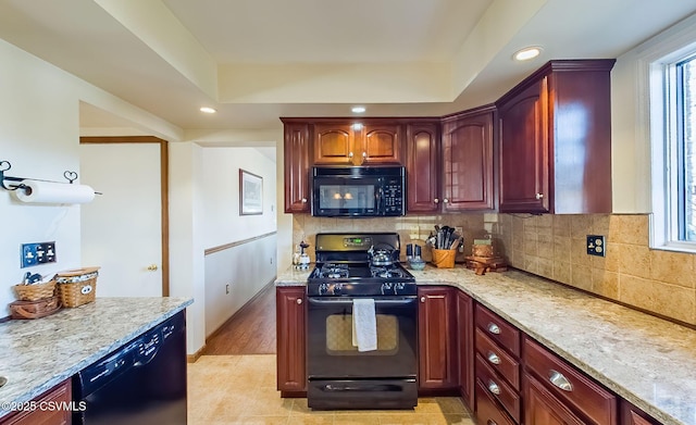 kitchen featuring dark brown cabinets, backsplash, black appliances, and light stone countertops