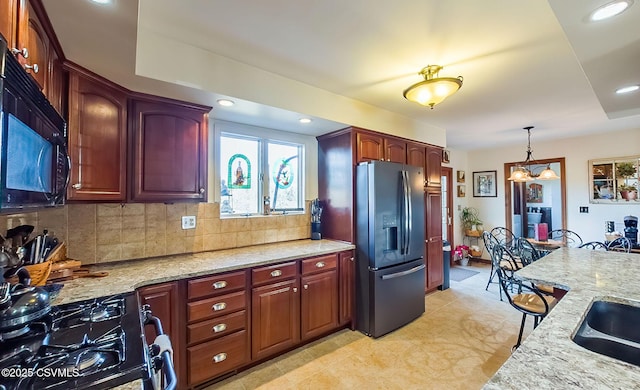 kitchen featuring tasteful backsplash, light stone counters, hanging light fixtures, black appliances, and recessed lighting