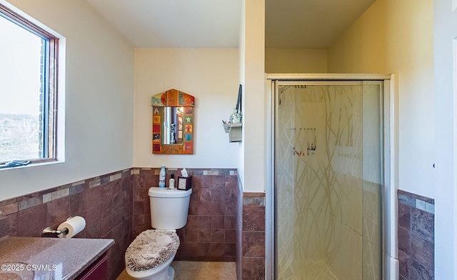 full bathroom featuring toilet, a wainscoted wall, vanity, a shower stall, and tile walls