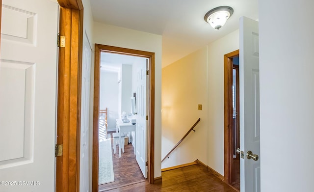 corridor featuring dark wood-style flooring, baseboards, and an upstairs landing