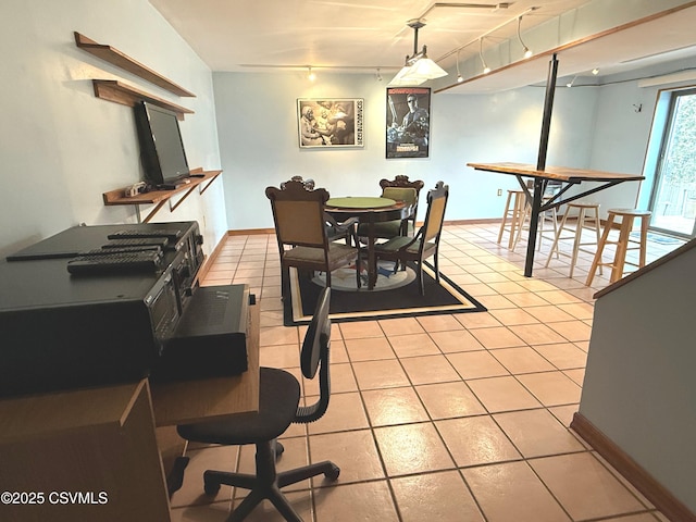 dining area with light tile patterned floors, baseboards, and track lighting