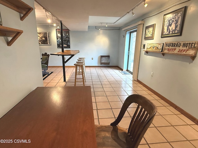 unfurnished dining area featuring heating unit, light tile patterned floors, baseboards, and rail lighting