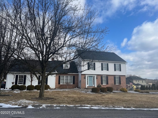 view of front of property featuring brick siding and a chimney