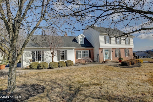 colonial home with a front yard, a chimney, and brick siding