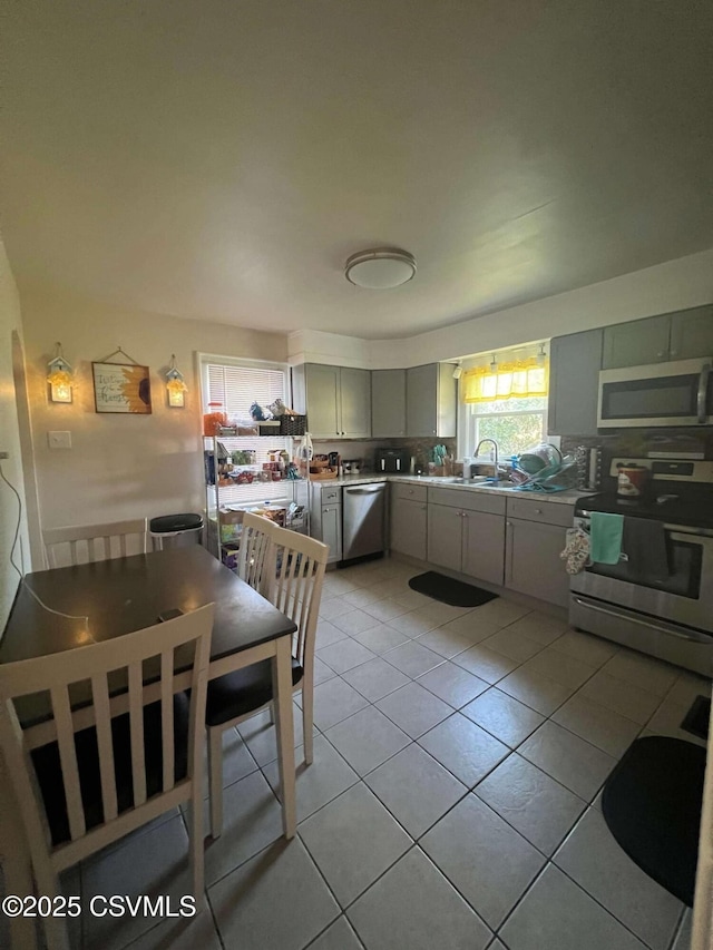 kitchen with light tile patterned floors, stainless steel appliances, and a sink