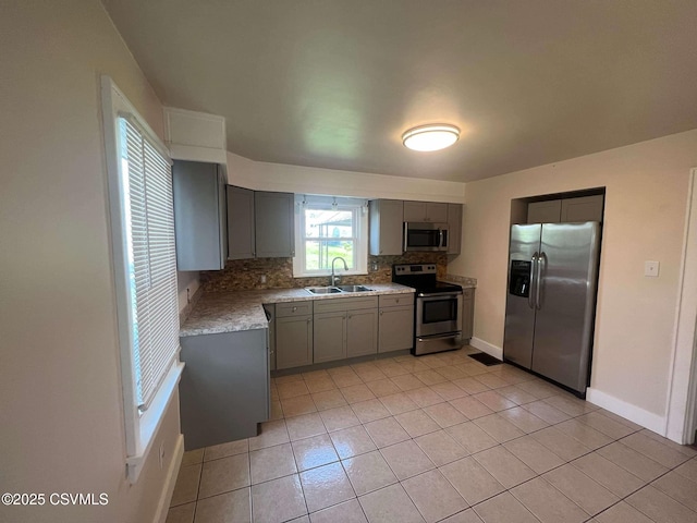 kitchen with light tile patterned flooring, a sink, light countertops, appliances with stainless steel finishes, and tasteful backsplash