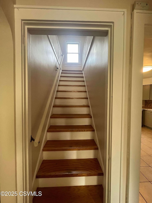 staircase featuring arched walkways and tile patterned floors