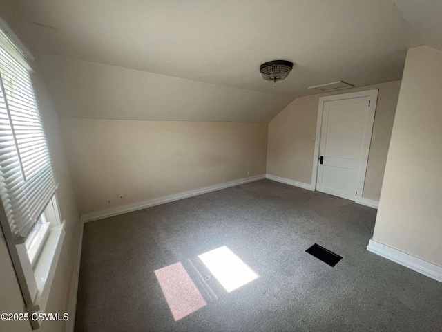 additional living space with vaulted ceiling, dark colored carpet, and baseboards