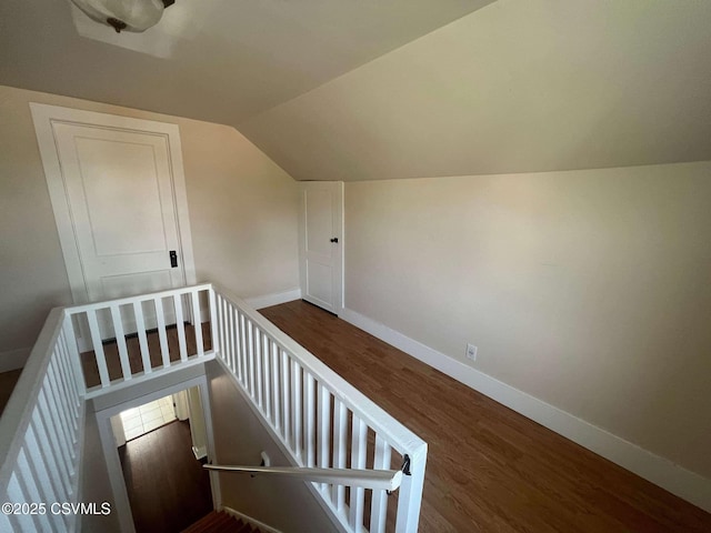 additional living space with vaulted ceiling, dark wood-style flooring, and baseboards