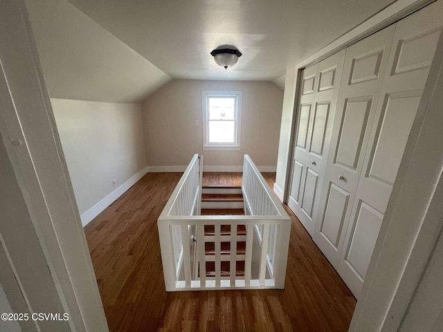 stairs with lofted ceiling, wood finished floors, and baseboards