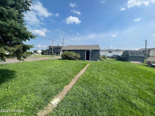 view of yard featuring a storage shed, an outbuilding, and fence