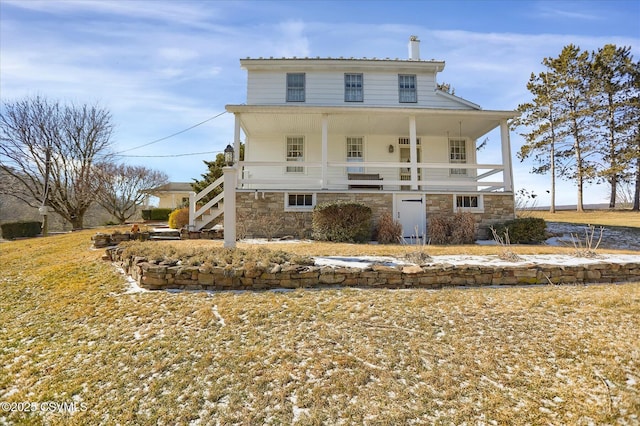 view of front facade with a porch, stone siding, and a chimney