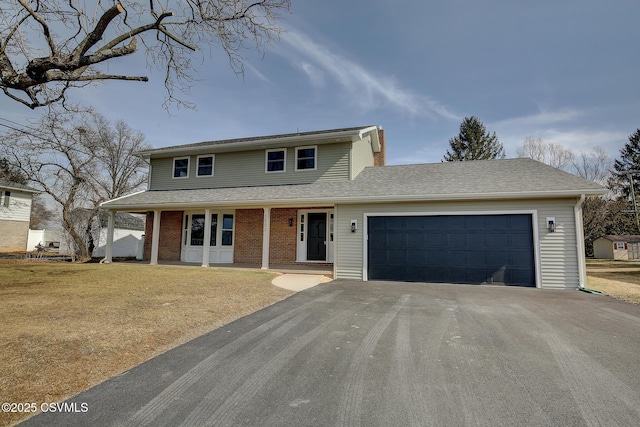 traditional-style home with aphalt driveway, an attached garage, brick siding, a shingled roof, and a front lawn