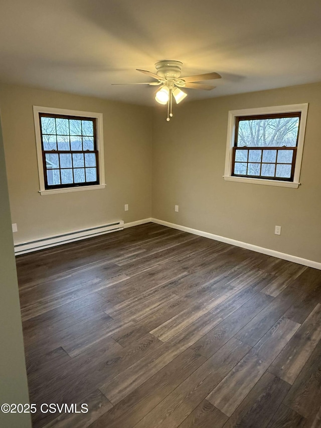 unfurnished room with a baseboard heating unit, a healthy amount of sunlight, ceiling fan, and dark wood-type flooring