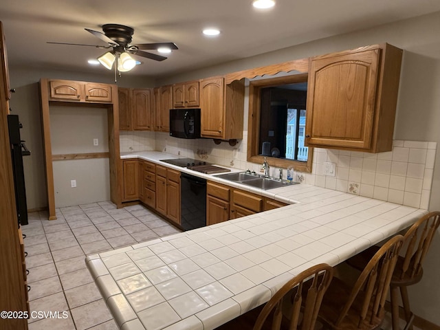 kitchen with decorative backsplash, tile countertops, a peninsula, black appliances, and a sink