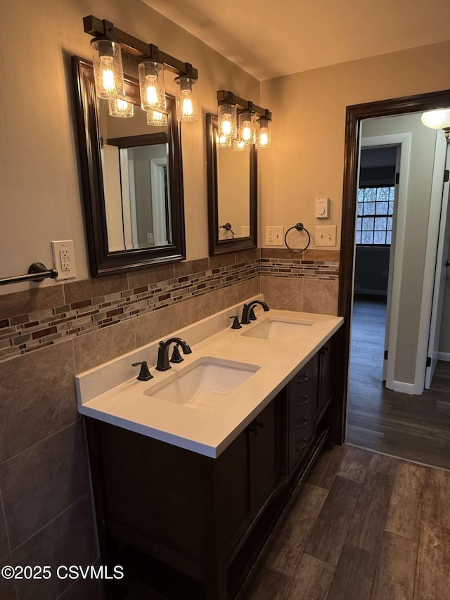 bathroom with double vanity, a sink, tile walls, and wood finished floors