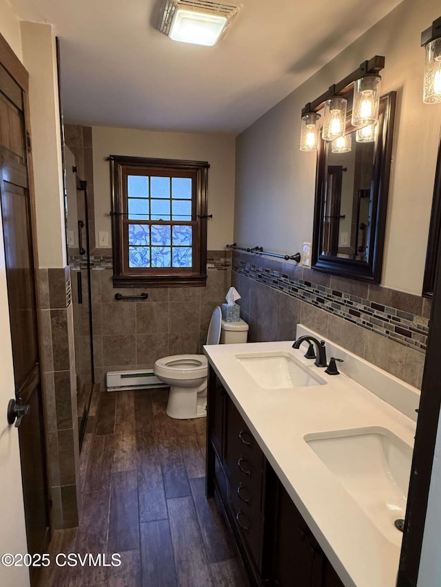 full bathroom featuring a baseboard radiator, a sink, tile walls, and double vanity