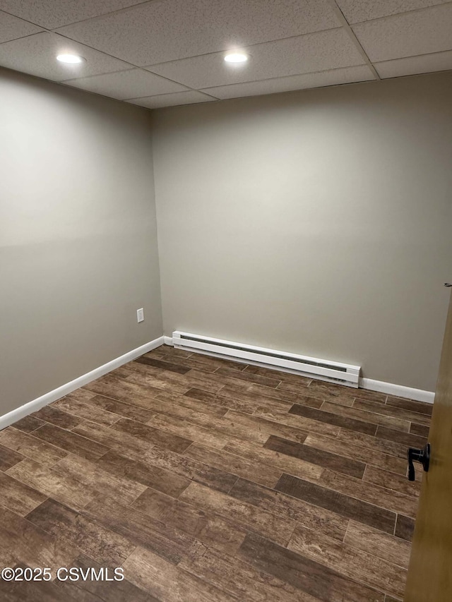 empty room featuring dark wood-type flooring, a baseboard radiator, and baseboards