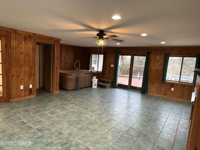 interior space featuring wood walls, baseboards, a ceiling fan, and recessed lighting