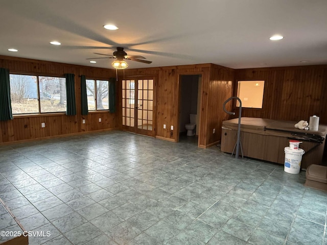 kitchen featuring baseboards, a ceiling fan, french doors, wood walls, and recessed lighting