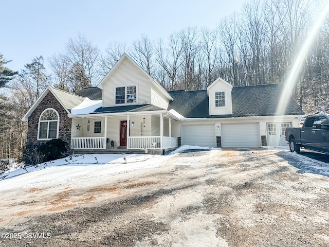 view of front of house with covered porch, driveway, stone siding, and an attached garage