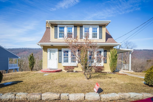 view of front of property featuring a shingled roof and a front lawn