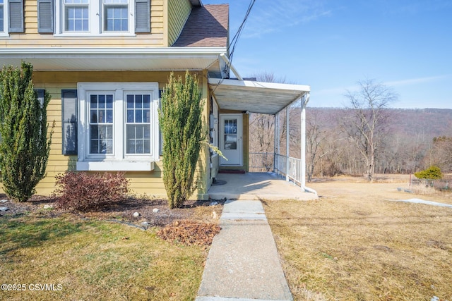 property entrance with a shingled roof and a yard