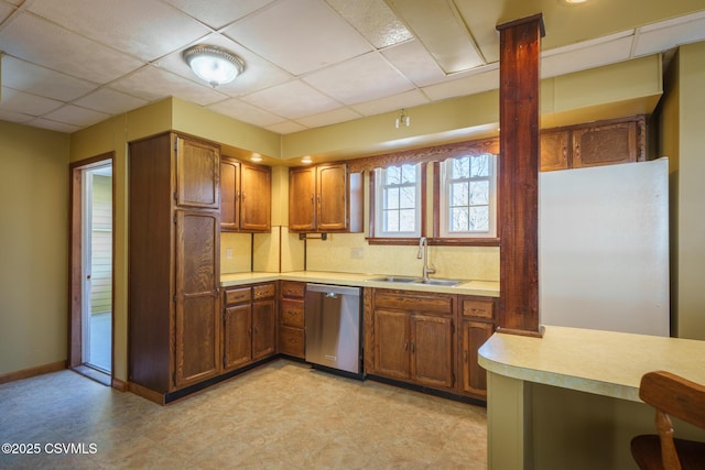 kitchen featuring a sink, brown cabinetry, light countertops, and dishwasher