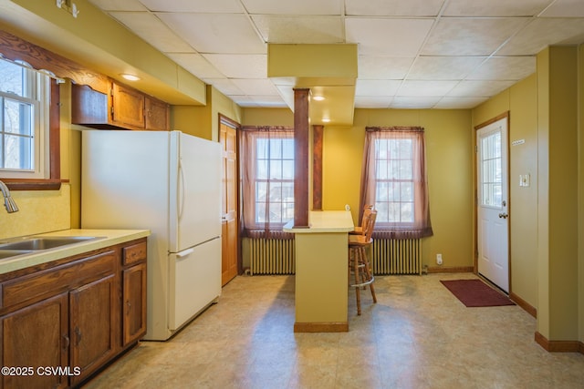 kitchen with radiator, a kitchen bar, light countertops, and a sink