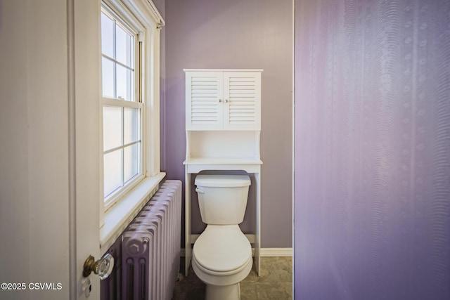 bathroom featuring radiator heating unit, toilet, and baseboards