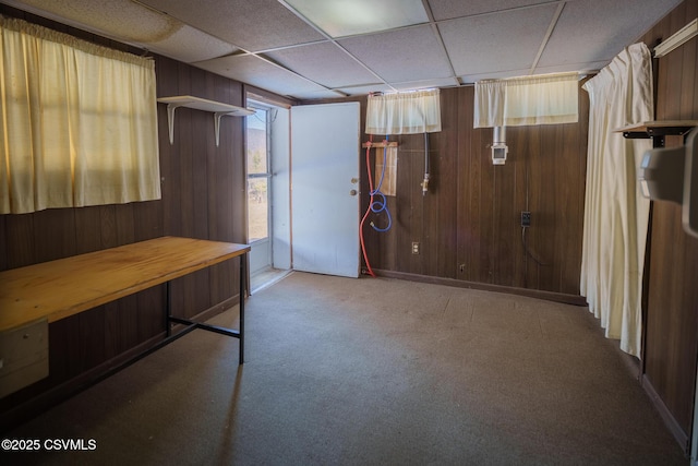 interior space featuring carpet floors, wood walls, and a paneled ceiling