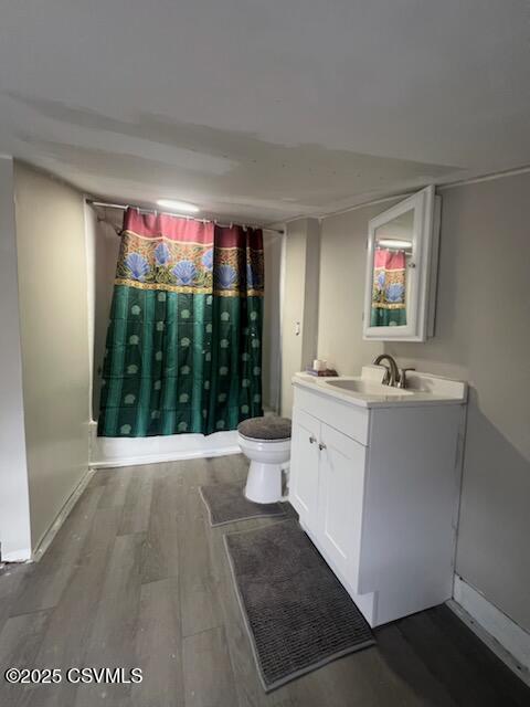 bathroom with toilet, a shower with curtain, wood finished floors, and vanity