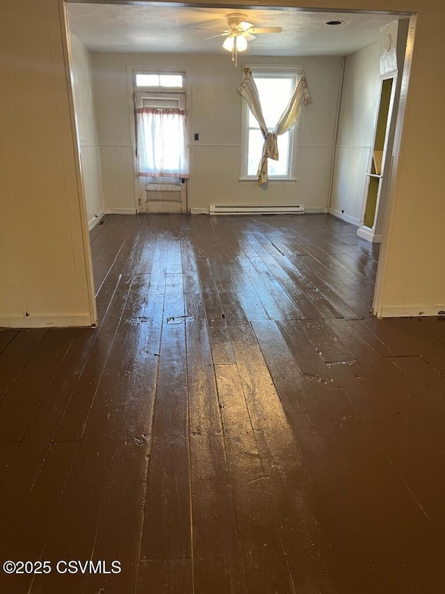 spare room with dark wood-type flooring, a baseboard heating unit, and a ceiling fan