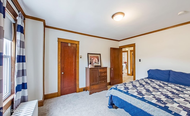 carpeted bedroom with ornamental molding and baseboards