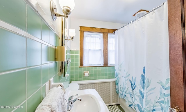 bathroom featuring shower / bath combo with shower curtain, a sink, and tile walls