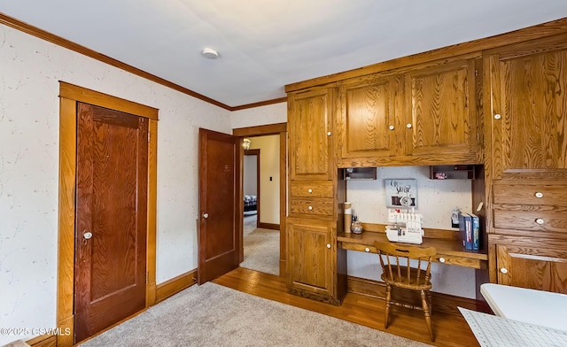 kitchen featuring brown cabinets, crown molding, baseboards, and wood finished floors