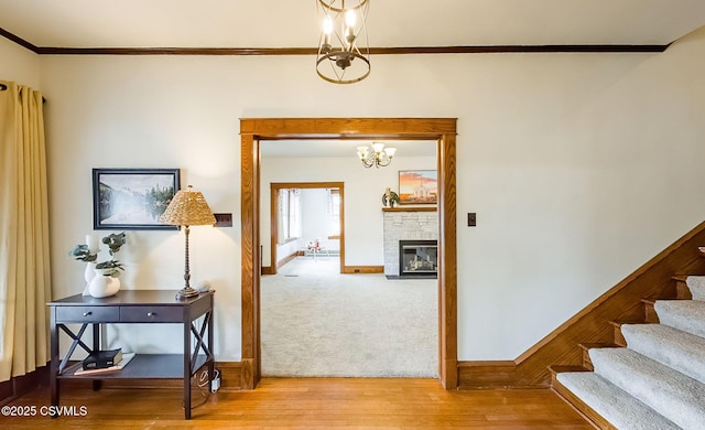 hall featuring an inviting chandelier, ornamental molding, wood finished floors, baseboards, and stairs