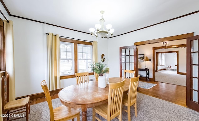 dining room featuring plenty of natural light, ornamental molding, a notable chandelier, and wood finished floors