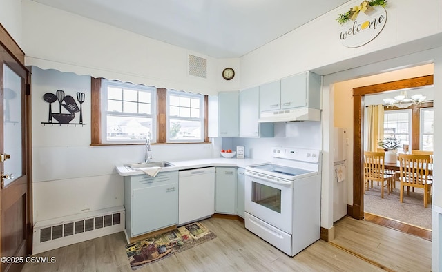 kitchen with white appliances, light wood finished floors, radiator, under cabinet range hood, and a sink