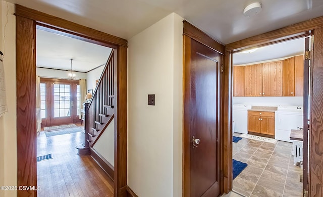 corridor featuring visible vents, stairs, washer / clothes dryer, and a notable chandelier